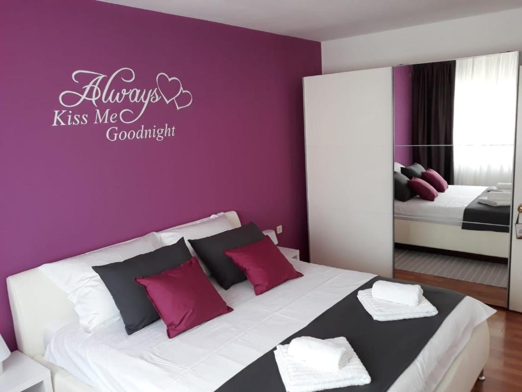 ein Schlafzimmer mit einem Bett mit einer lila Wand in der Unterkunft Apartman Kristian in Velika Gorica