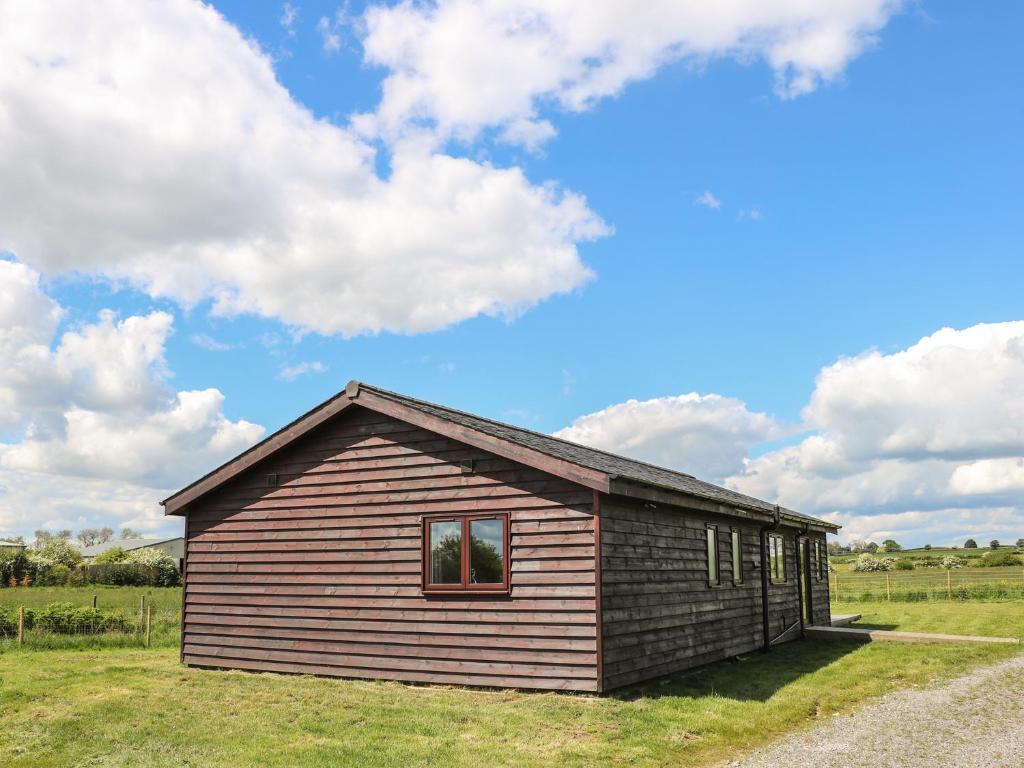 a small wooden building in a field with a cloudy sky at Rose Lodge in York