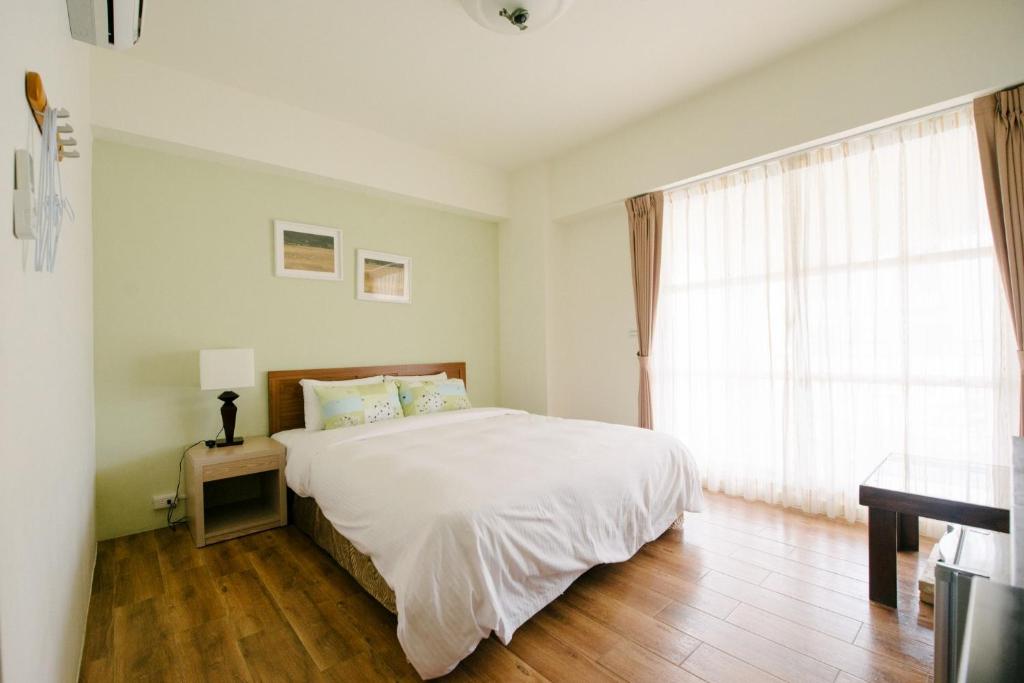 a bedroom with a white bed and a window at He Sen B&B in Kenting