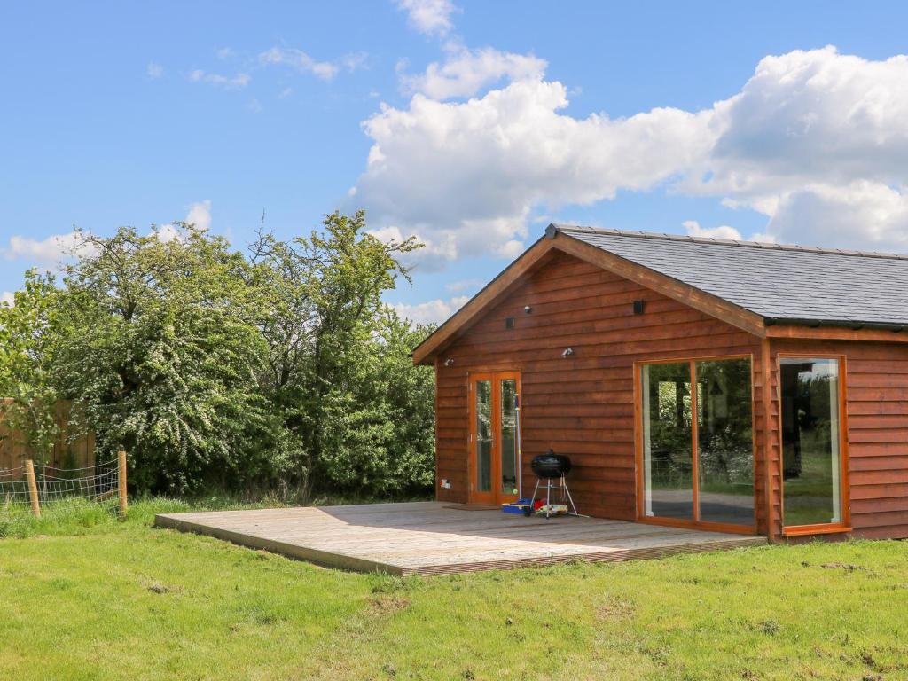 une petite cabine avec une terrasse dans un champ dans l'établissement Oak Lodge, à York