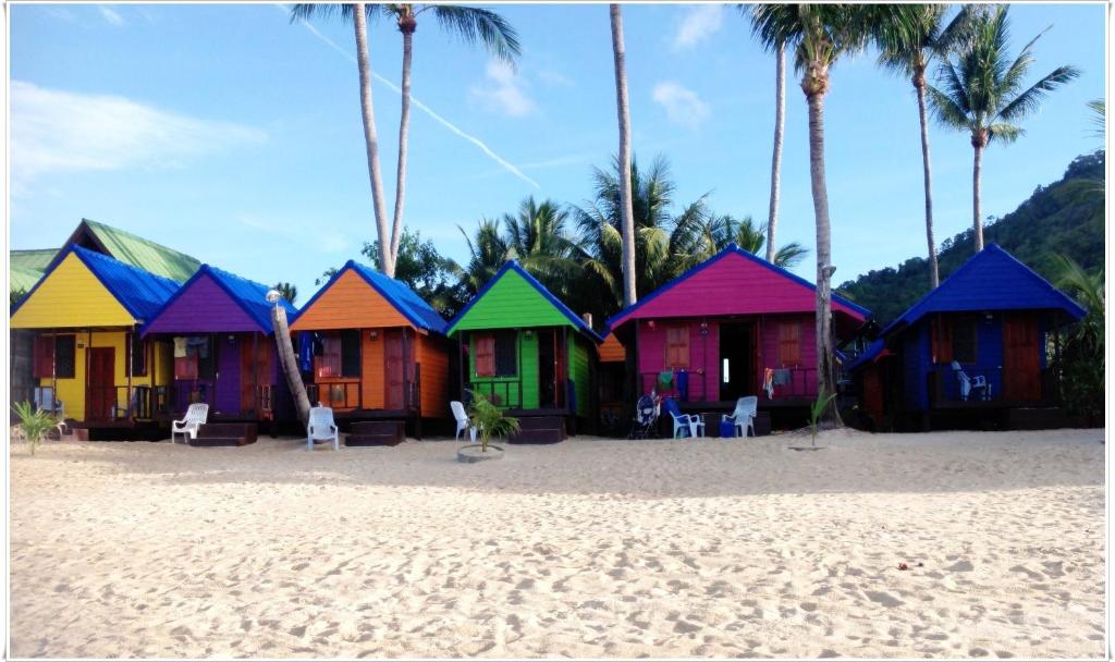 una fila de casas coloridas en una playa en New Hut Bungalow en Lamai Beach