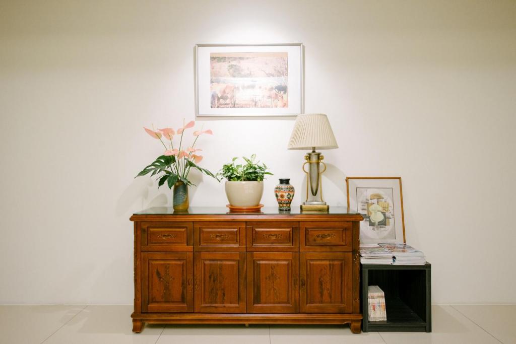 a wooden dresser with a lamp and plants on it at He Sen B&B in Kenting