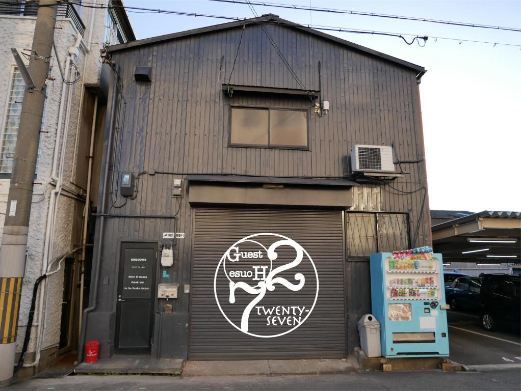 un edificio con una puerta de garaje con un cartel. en Guest House Twenty-Seven 27 en Osaka