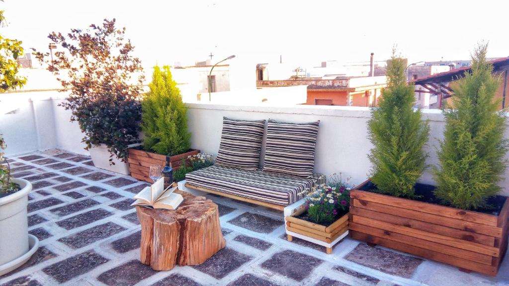 une terrasse avec un banc en bois et des plantes en pot dans l'établissement R&G Salento, à Porto Cesareo