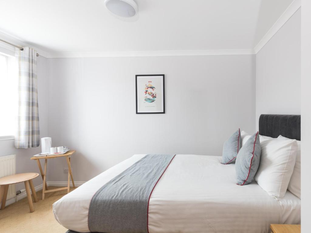 a white bedroom with a bed and a table at Clydesdale Hotel in Hamilton