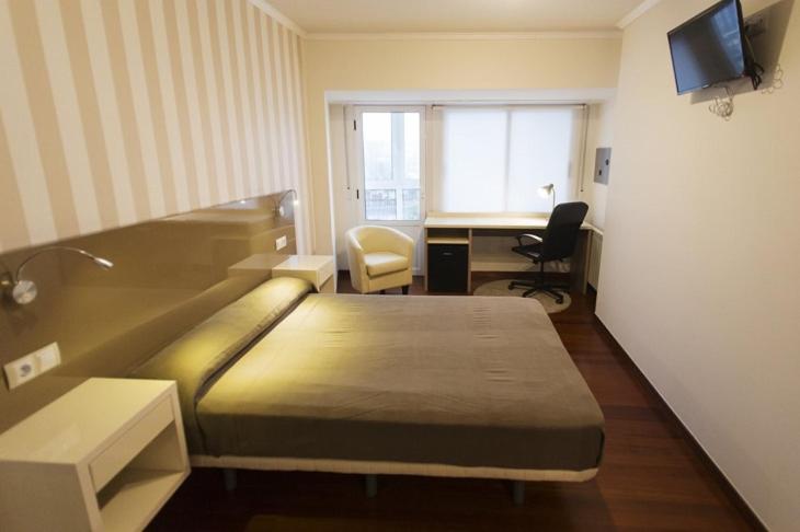 ein Hotelzimmer mit einem Bett und einem Schreibtisch mit einem Computer in der Unterkunft Residencia Compostela in Santiago de Compostela