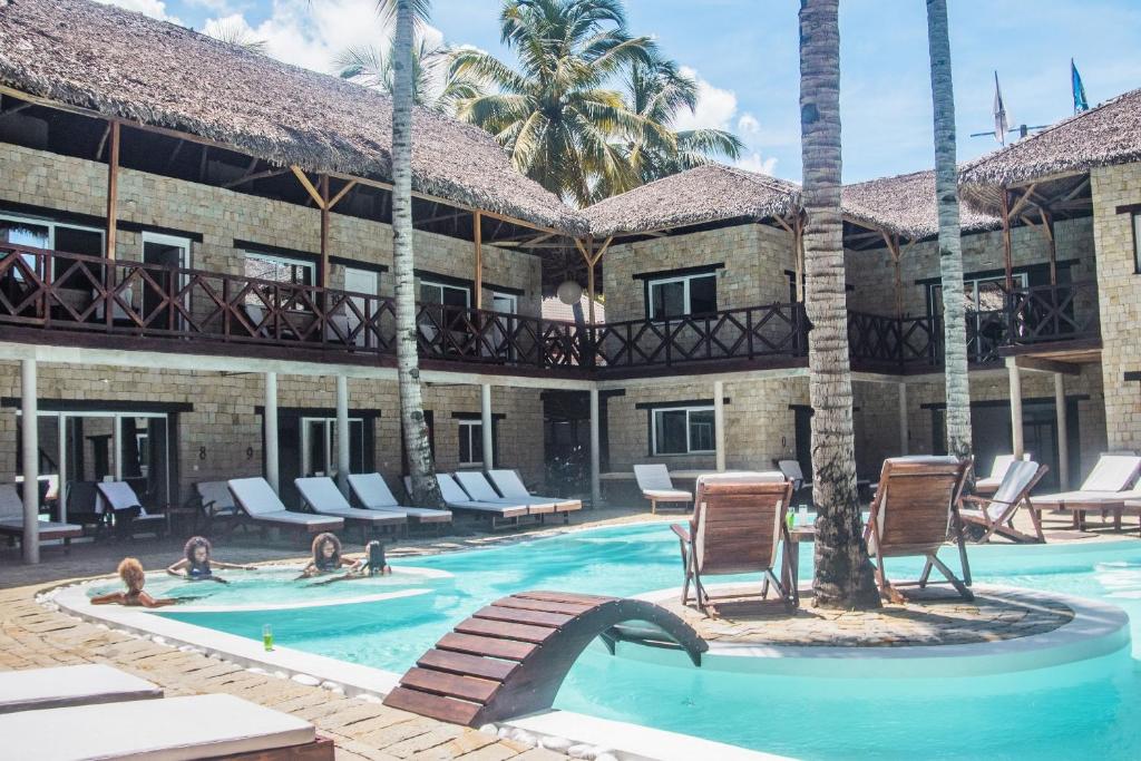 un complejo con piscina y palmeras en Hotel La Bombonera en Nosy Be