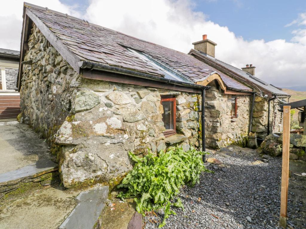 an old stone house with a garden in front of it at Waterfall Cottage in Caernarfon