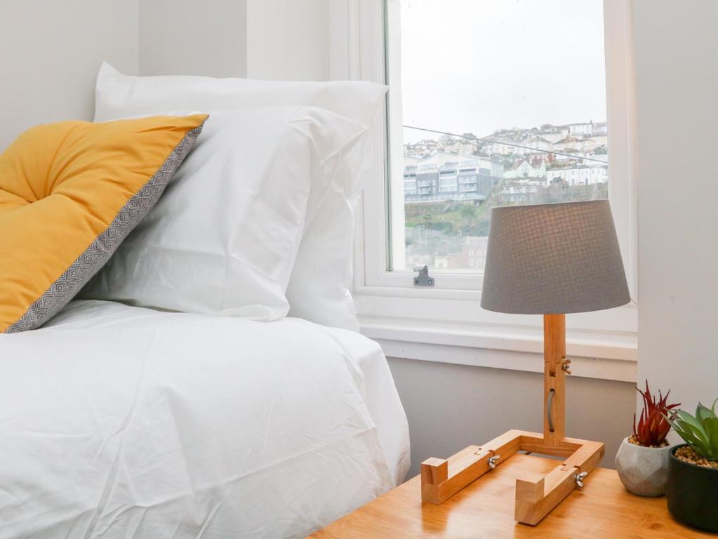 a bed with white sheets and a lamp on a table at SeaSound in Ilfracombe