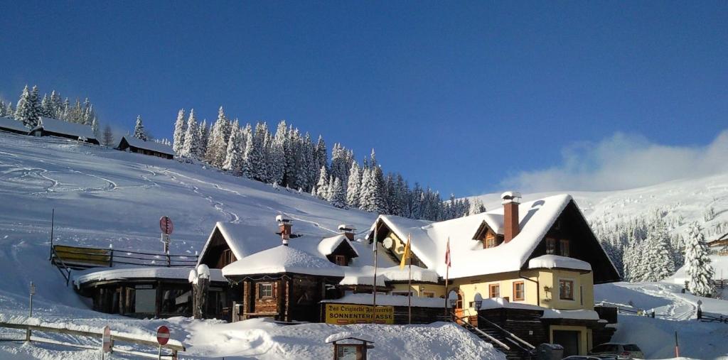 un edificio cubierto de nieve en la cima de una montaña en Appartements Futtertrögl, en Lachtal