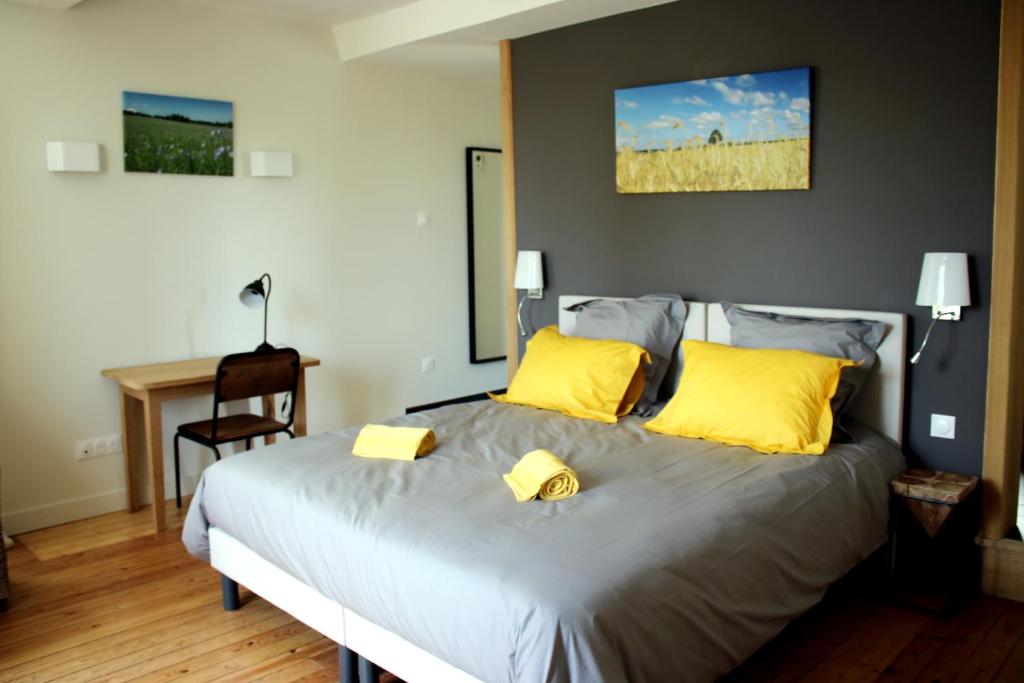 a bedroom with a bed with yellow pillows and a desk at Safranière de la Venelle du Moulin in Jort