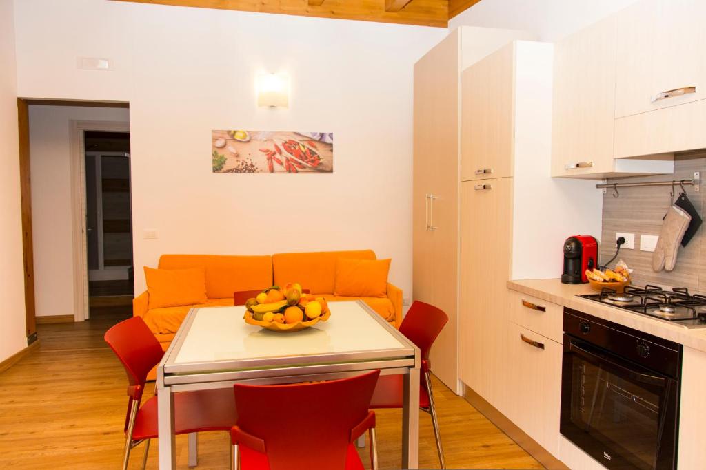 cocina y sala de estar con mesa y sofá naranja en Appartamenti Vacanze Mareemare en Capo dʼOrlando