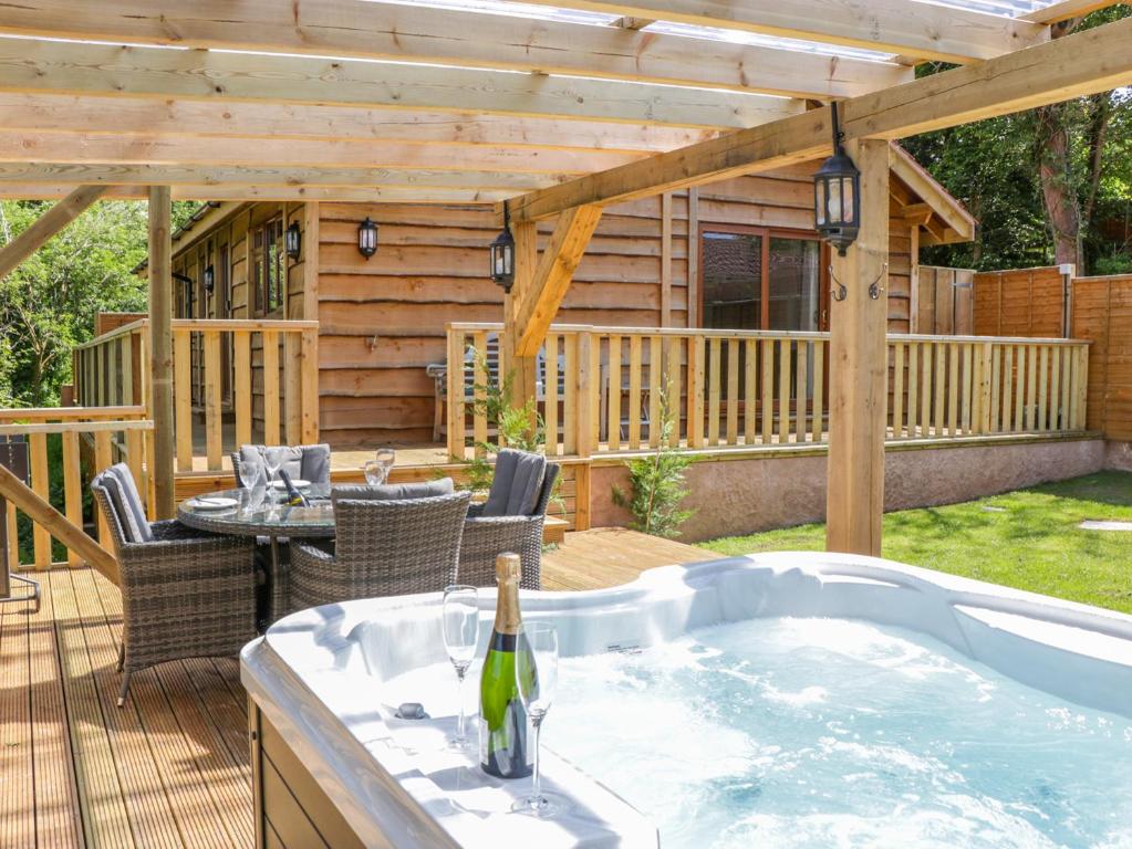 a hot tub on a deck with a pergola at Elm Lodge in Watchet