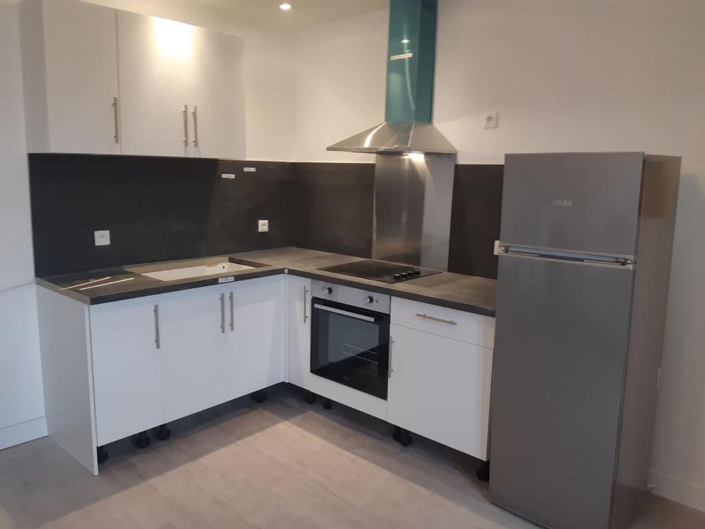 a kitchen with white cabinets and a stainless steel refrigerator at Guibert 17 F2 47 m2 Caudebec étage 1 SWEET HOME in Caudebec-lès-Elbeuf