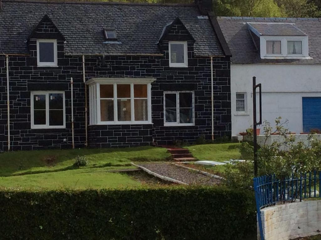 une maison en brique noire avec un blanc dans l'établissement Cliff Cottage, à Kyle of Lochalsh