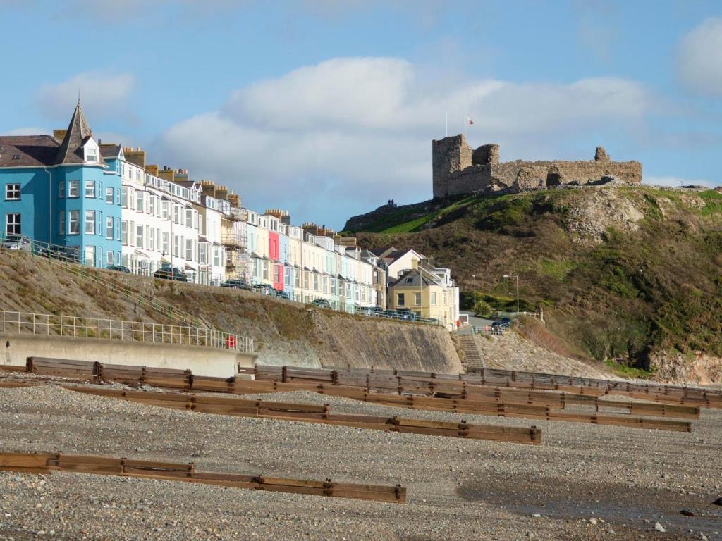 a row of buildings on a hill with a castle at The Towers - Llyn in Criccieth