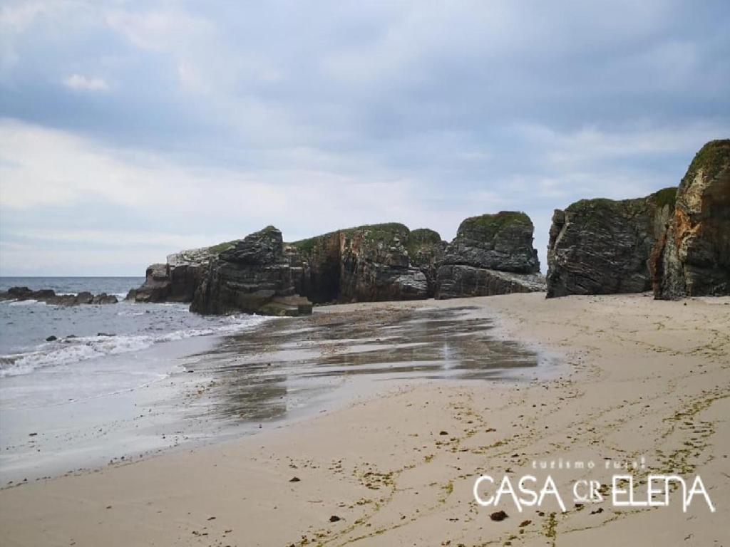 a sandy beach with rocks in the ocean at Casa Elena Turismo Rural in Reinante