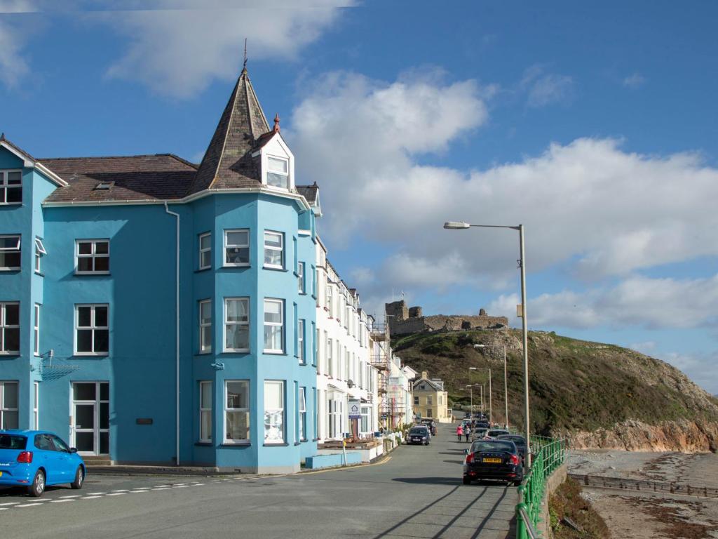 a blue building on a street with a castle in the background at The Towers - Ardudwy in Criccieth