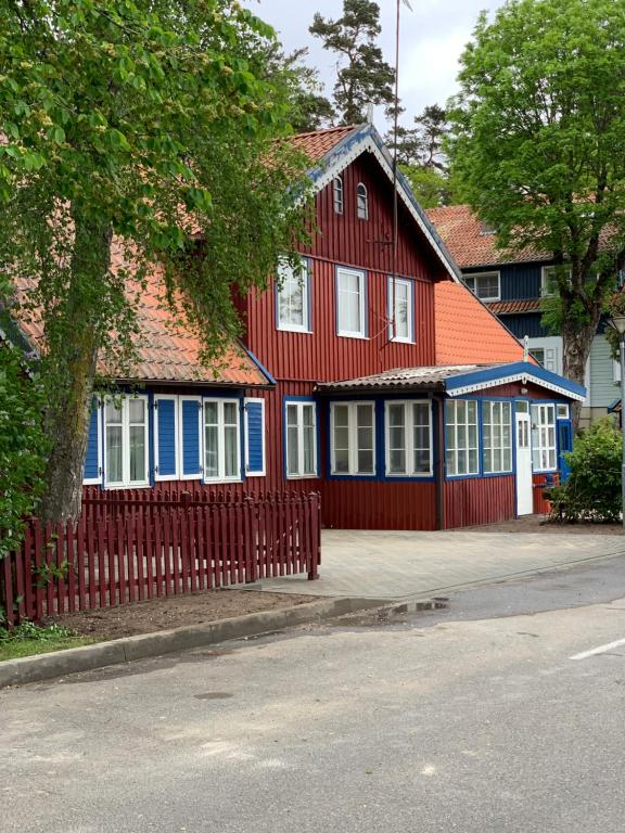 una casa roja y azul con una valla roja en Skruzdynes 11, en Nida