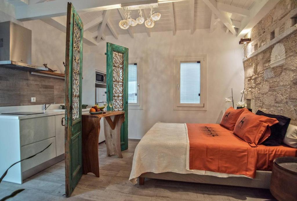 a bedroom with a bed with an orange blanket and a kitchen at Eftopia Beachfront Studio in Kokkari