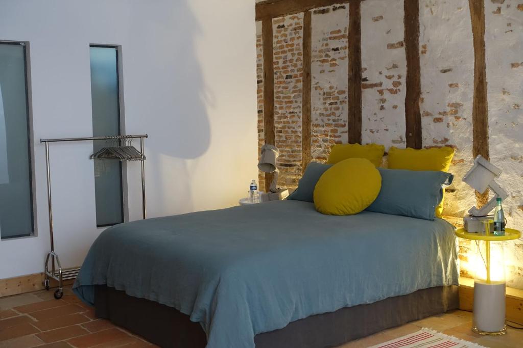 - une chambre avec un lit doté d'oreillers bleus et jaunes dans l'établissement Impasse du Boeuf, à Lavaur