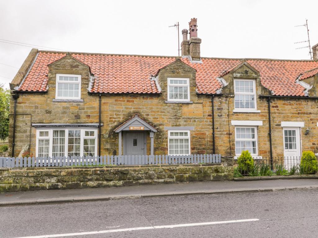 an old brick house with a white fence at 11A High Street in Scarborough