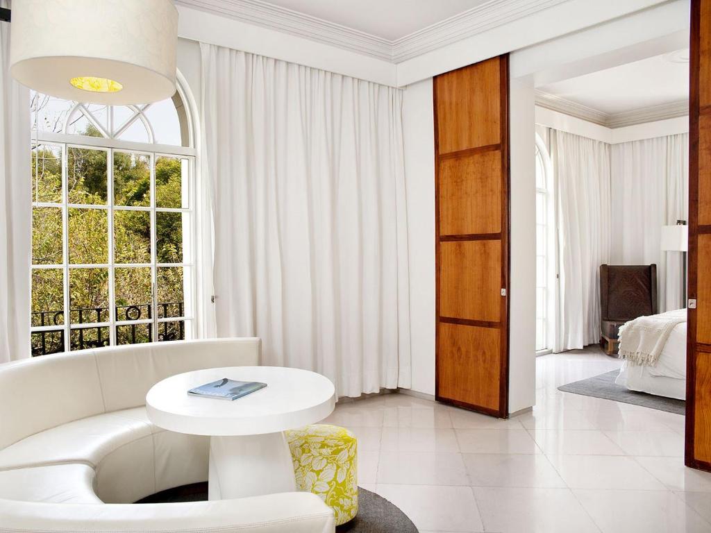 a white living room with a white couch and a table at Condesa df, Mexico City, a Member of Design Hotels in Mexico City