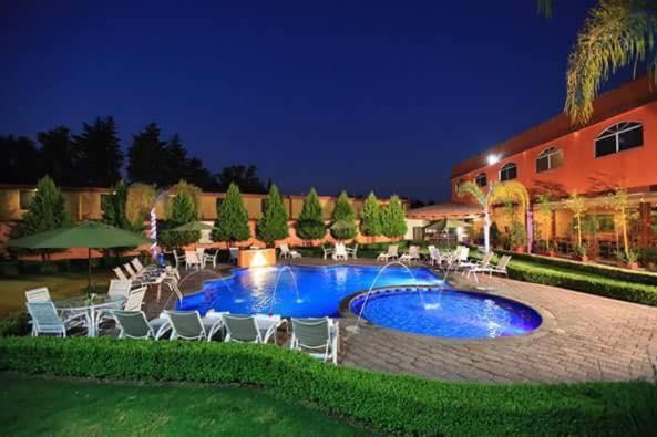 a large swimming pool with chairs and a building at GS Quinto Sol Teotihuacan in San Juan Teotihuacán