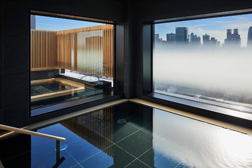 um quarto com duas janelas com vista para a cidade em ONSEN RYOKAN YUEN SHINJUKU em Tóquio