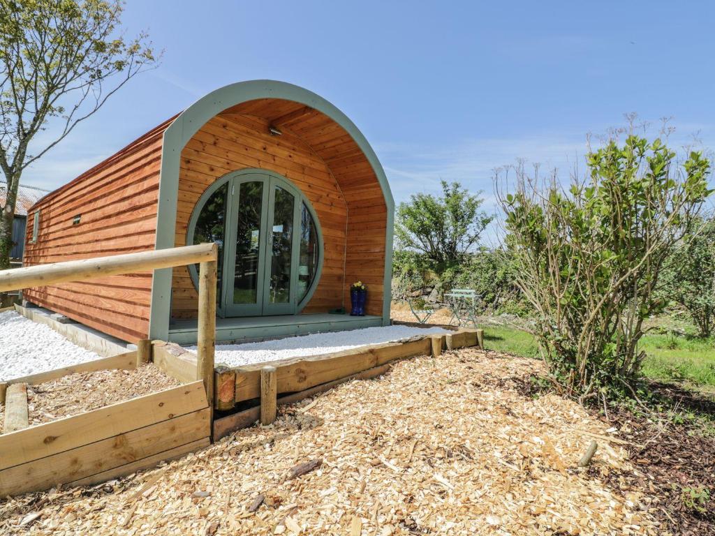 a small wooden house with a circular window at The Lamb Shack in Bodmin