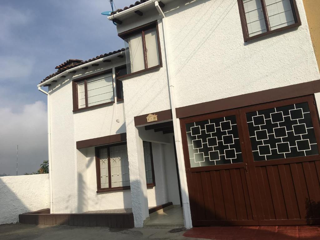 una casa bianca con garage marrone di Casa ENCANTO Paipa a Paipa