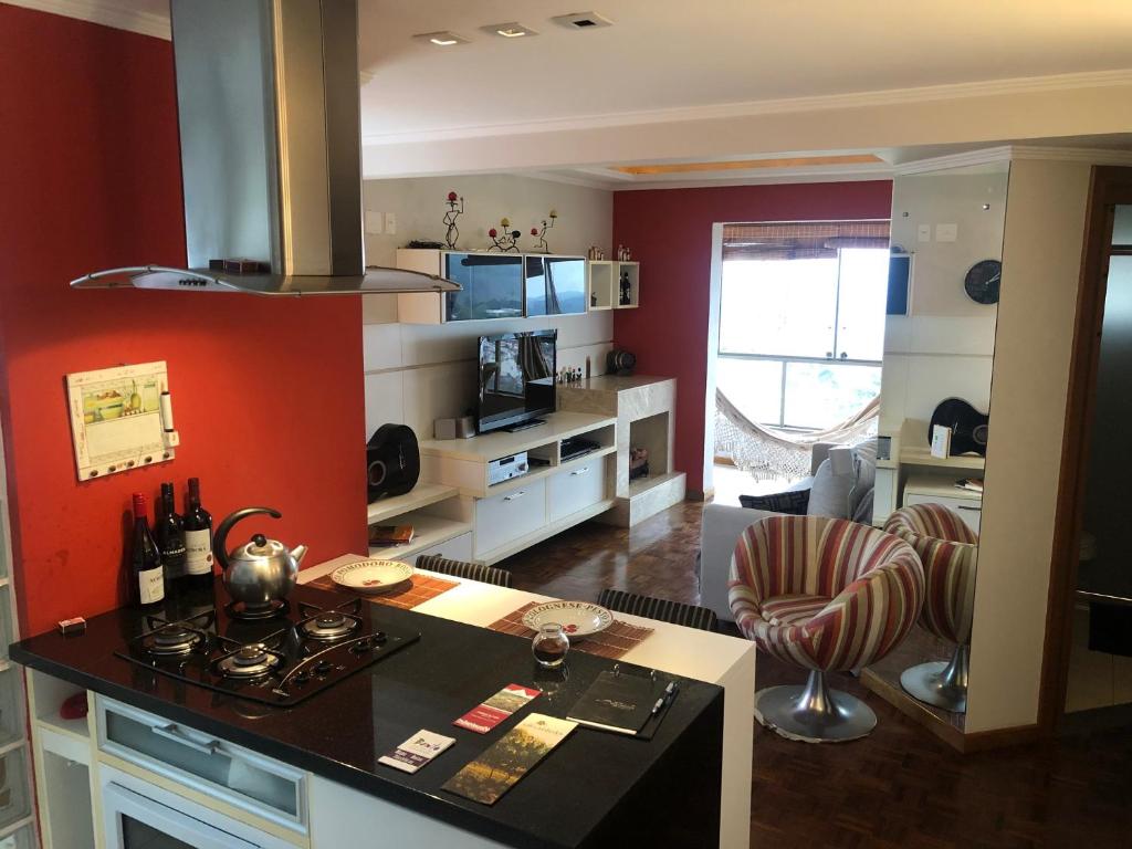 een keuken en een woonkamer met rode muren en een fornuis bij APTO FLAT LUXO 2 DORM Com VISTA VALE DOS VINHEDOS in Bento Gonçalves