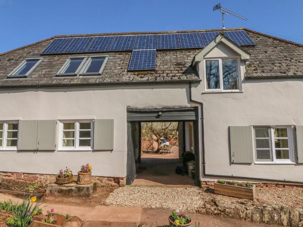 a white house with solar panels on the roof at Upper Barn Cottage in Minehead