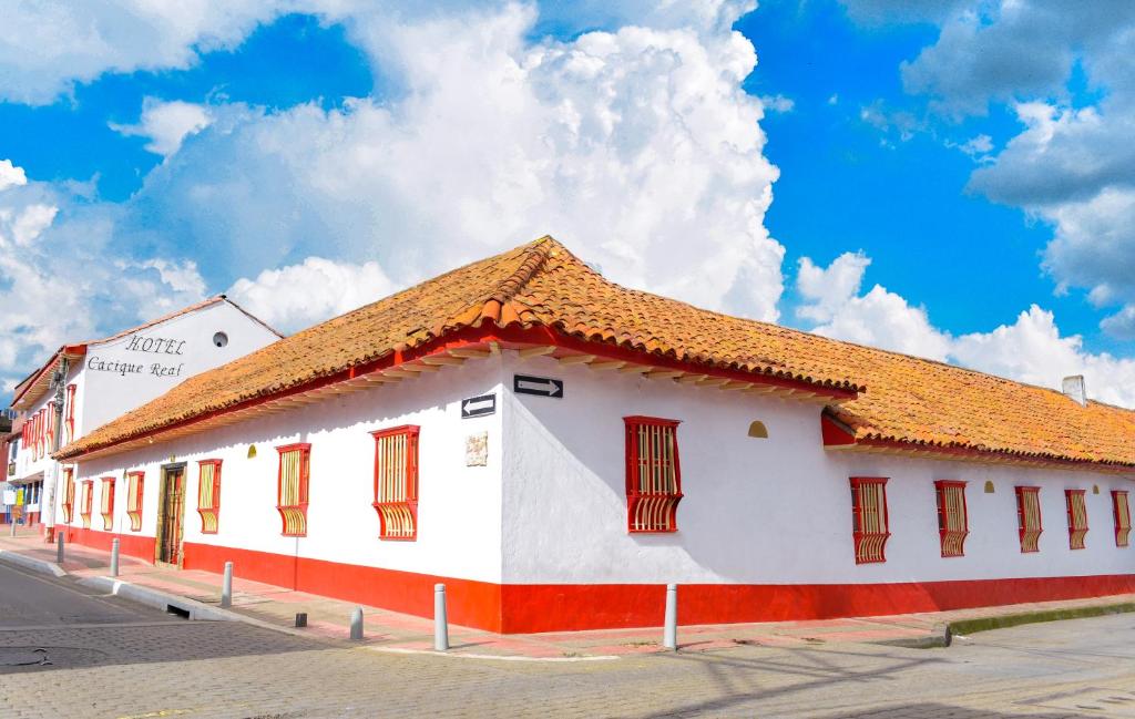 ein weißes Gebäude mit orangefarbenem Dach auf einer Straße in der Unterkunft Hotel Cacique Real in Zipaquirá