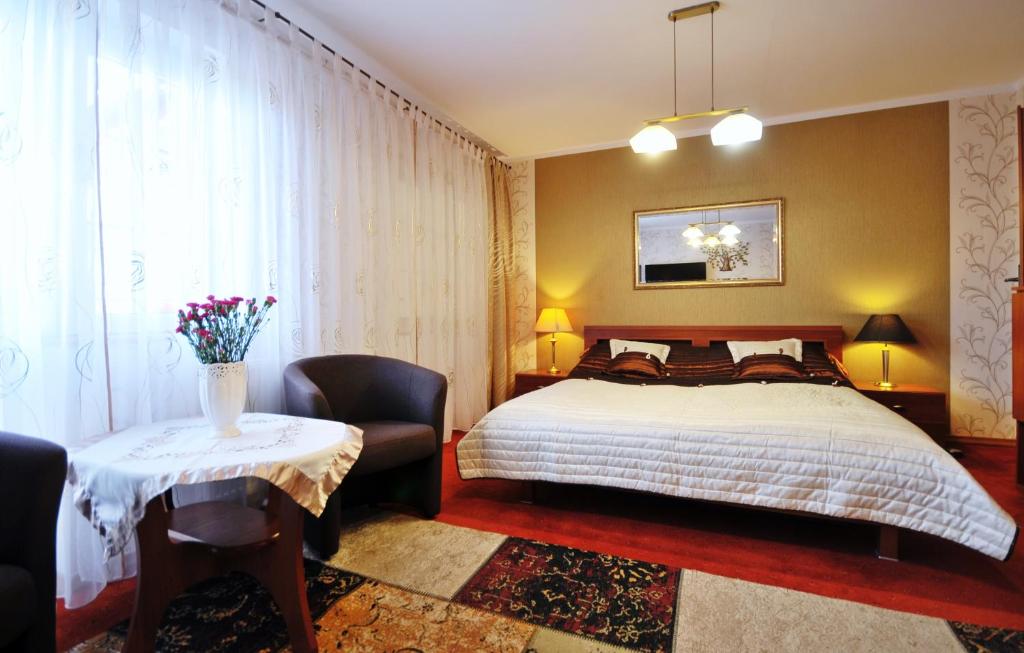 een slaapkamer met een bed en een tafel met een stoel bij Dworek Familijny in Kołobrzeg