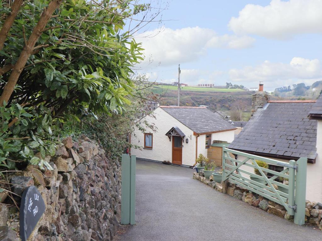 a cottage with a stone wall and a driveway at The Lily Pad in Camborne