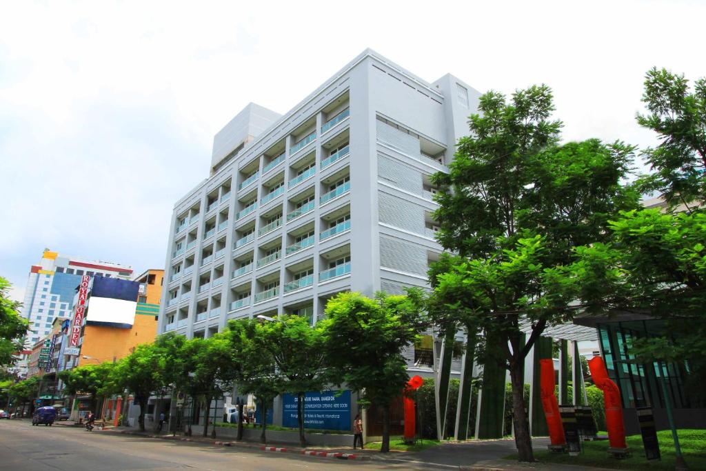 a white building on a city street with trees at GM Complex Apartment in Bangkok