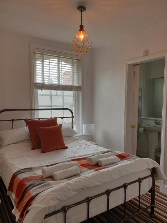 a bedroom with a large bed with orange pillows at The Studio Apartment in Weymouth