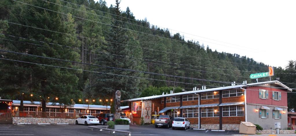 a building with cars parked in front of a mountain at Sitzmark Chalet Inn in Ruidoso
