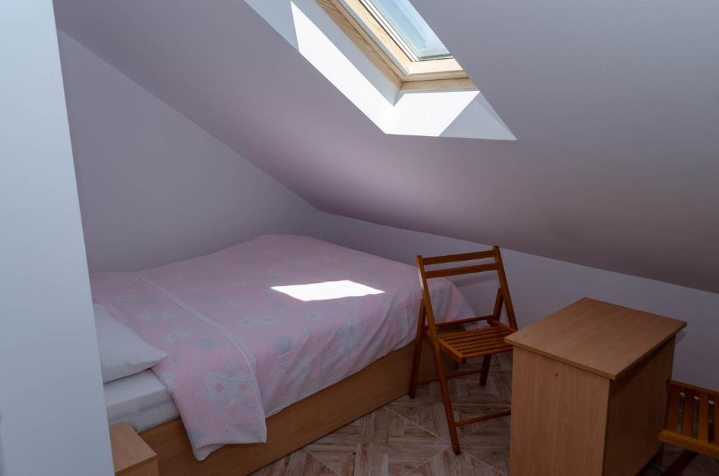 een slaapkamer op zolder met een bed en een stoel bij Mansarda mica cu baie proprie in Cluj-Napoca