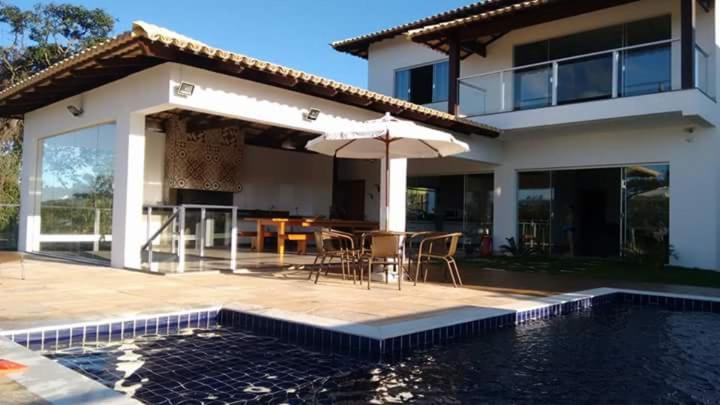 une maison avec une piscine, une table et un parasol dans l'établissement CASA UTOPIA ESCARPAS do LAGO, à Capitólio