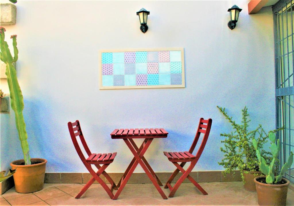 dos sillas rojas y una mesa frente a una pared azul en Il volo di Pindaro, en Siracusa