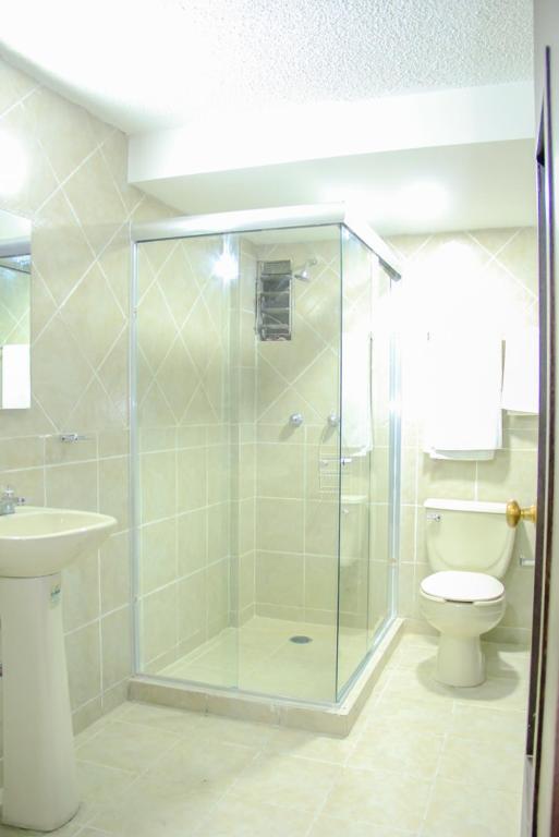 A tiled bathroom with a corner glass shower and toilet.