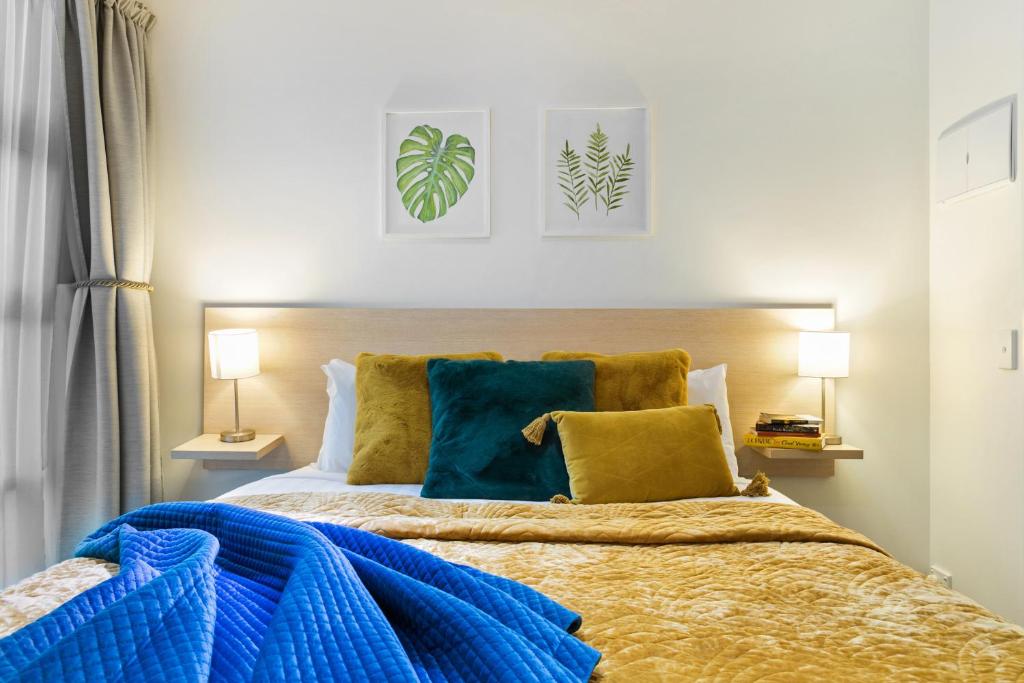 1 dormitorio con 1 cama con almohadas azules y amarillas en Deluxe Apartment with Sofa Bed - Sleeps 2 en Auckland