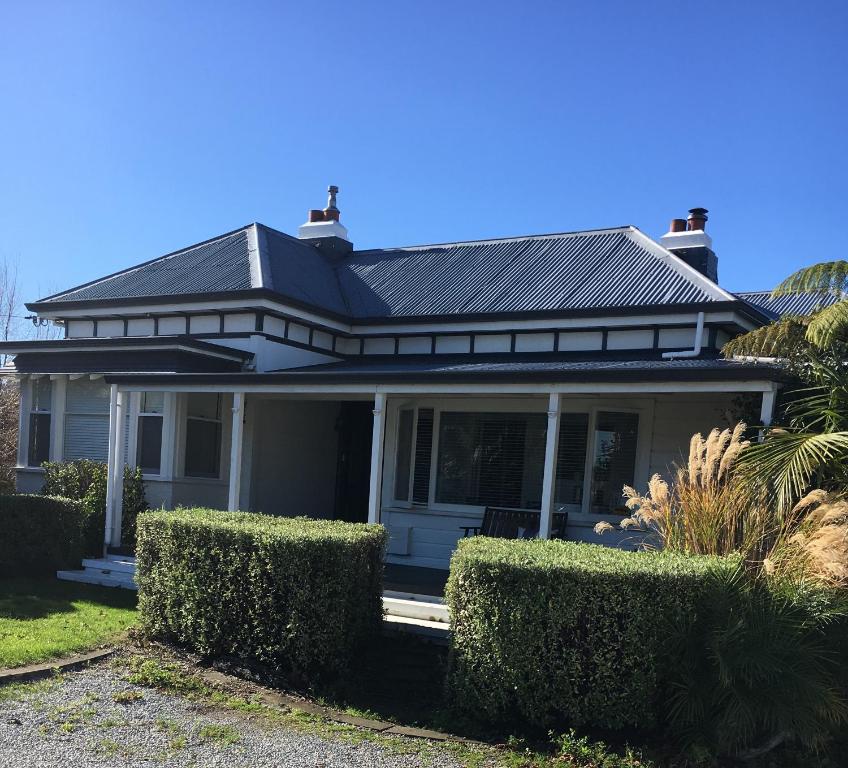 dom z czarnym dachem i krzakami w obiekcie Gisborne Dream Suite w mieście Gisborne