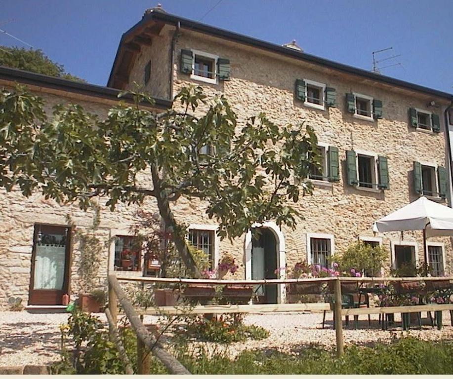 um grande edifício de pedra com uma árvore em frente em B&B Ca' Ori em Caprino Veronese