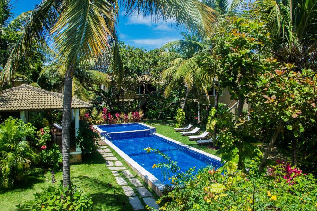 una piscina en un patio con palmeras en Aldeia das flores, en Pipa