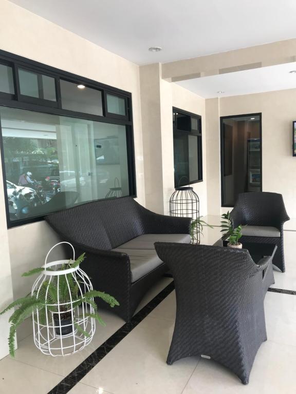sala de estar con sofá negro y ventana grande en Me Apartment, en Ban Talat Rangsit