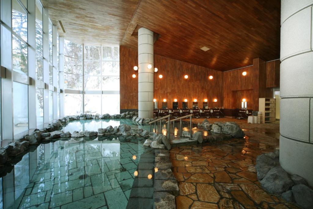 a large room with a pool of water in a building at Tomuraushionsen Higashi Taisetsuso in Shintoku