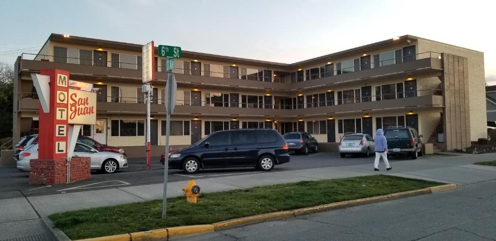 un gran edificio con coches estacionados en un estacionamiento en San Juan Motel, en Anacortes